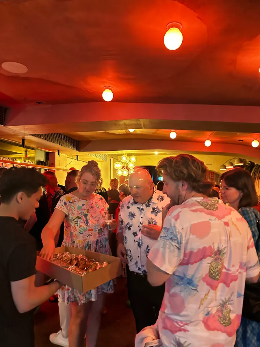 A Mister Minh waiter offering a box of bites to party guests